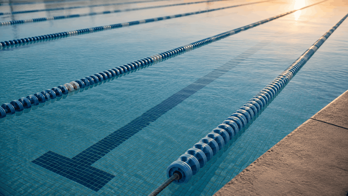 Floating lane ropes on the still water of an empty lap pool in early morning light
