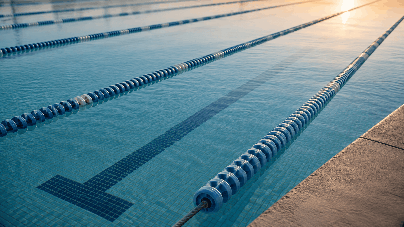 Floating lane ropes on the still water of an empty lap pool in early morning light
